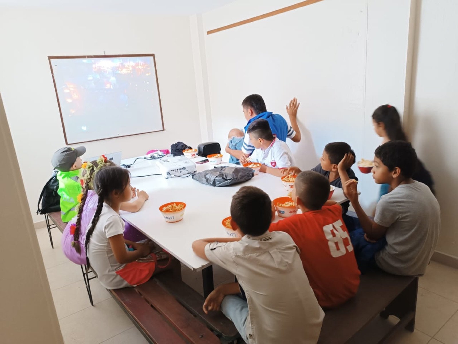 Niños viendo una proyección mientras comen su refrigerio